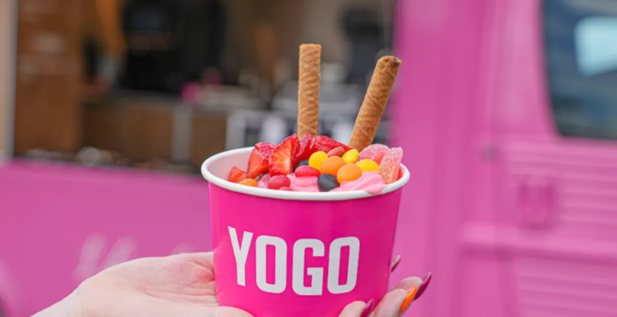 YOGO frozen yogurt med toppings foran den lyserøde YOGO-vogn